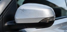 Espejo exterior de un auto con la carcasa dañada